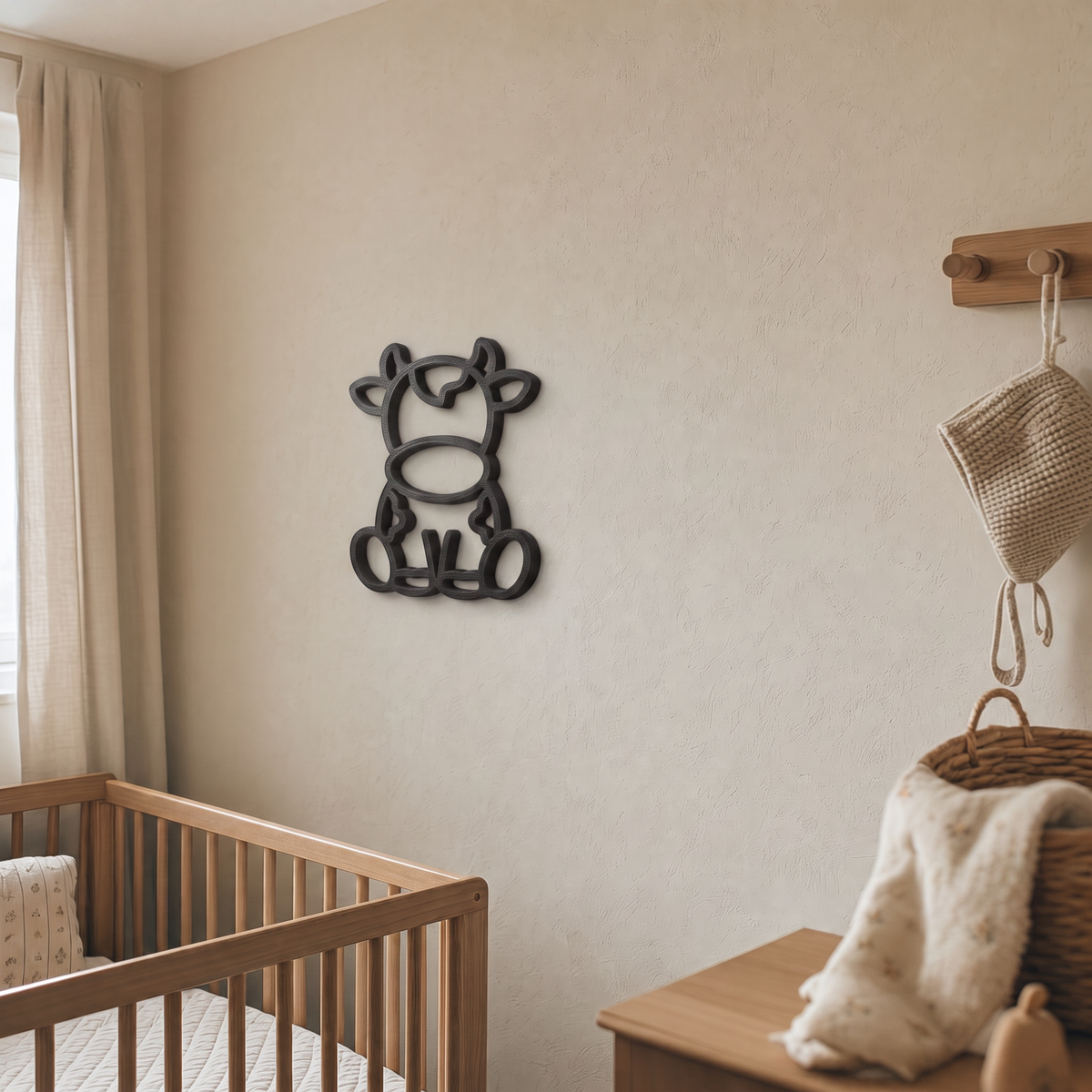 Black cow wall art beside a wooden peg rail in a nursery